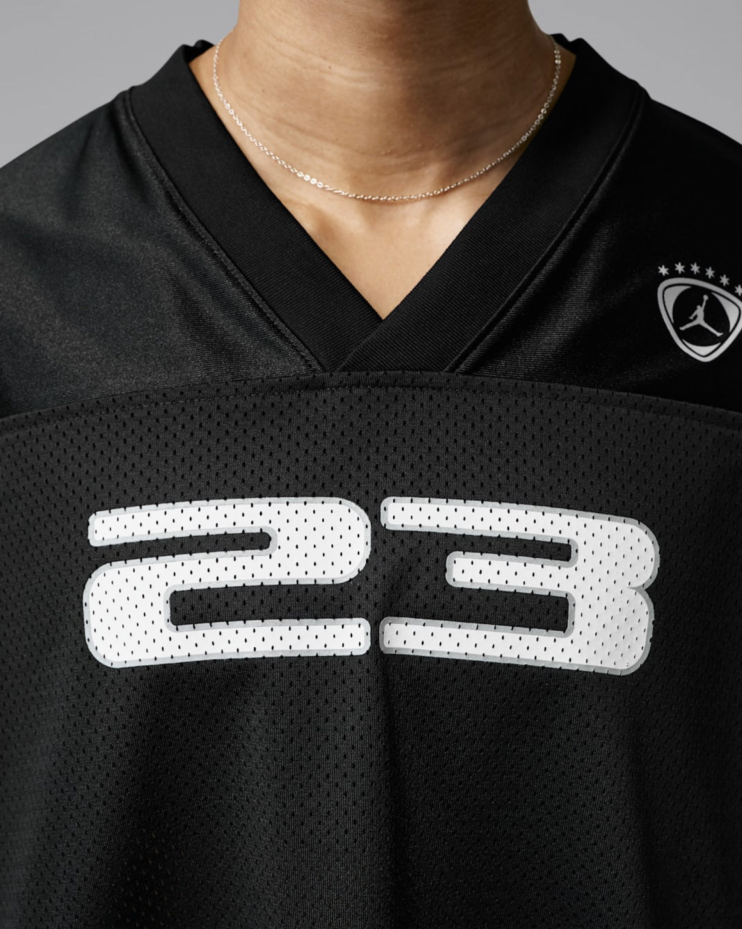 Close-up of black mesh jersey with white "23" numbering and Jordan star crest at shoulder