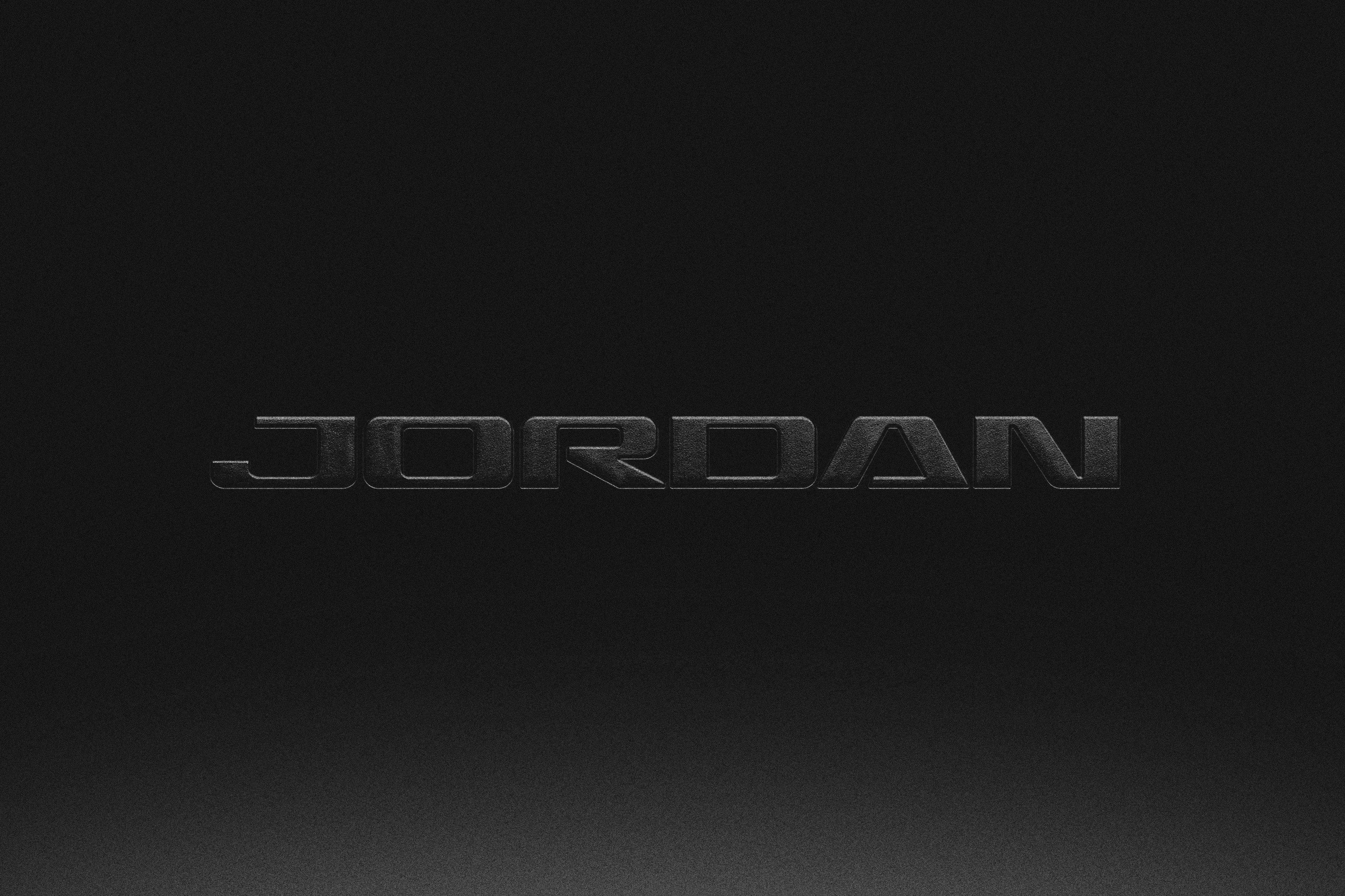 Dark embossed Jordan wordmark on textured black surface with subtle gradient lighting